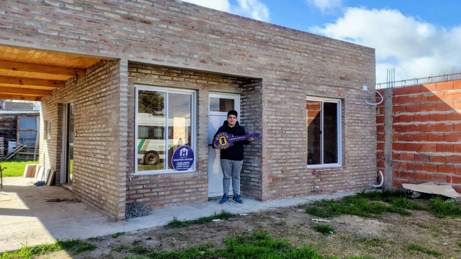 Cliente recibiendo la llave frente a su vivienda de ladrillo